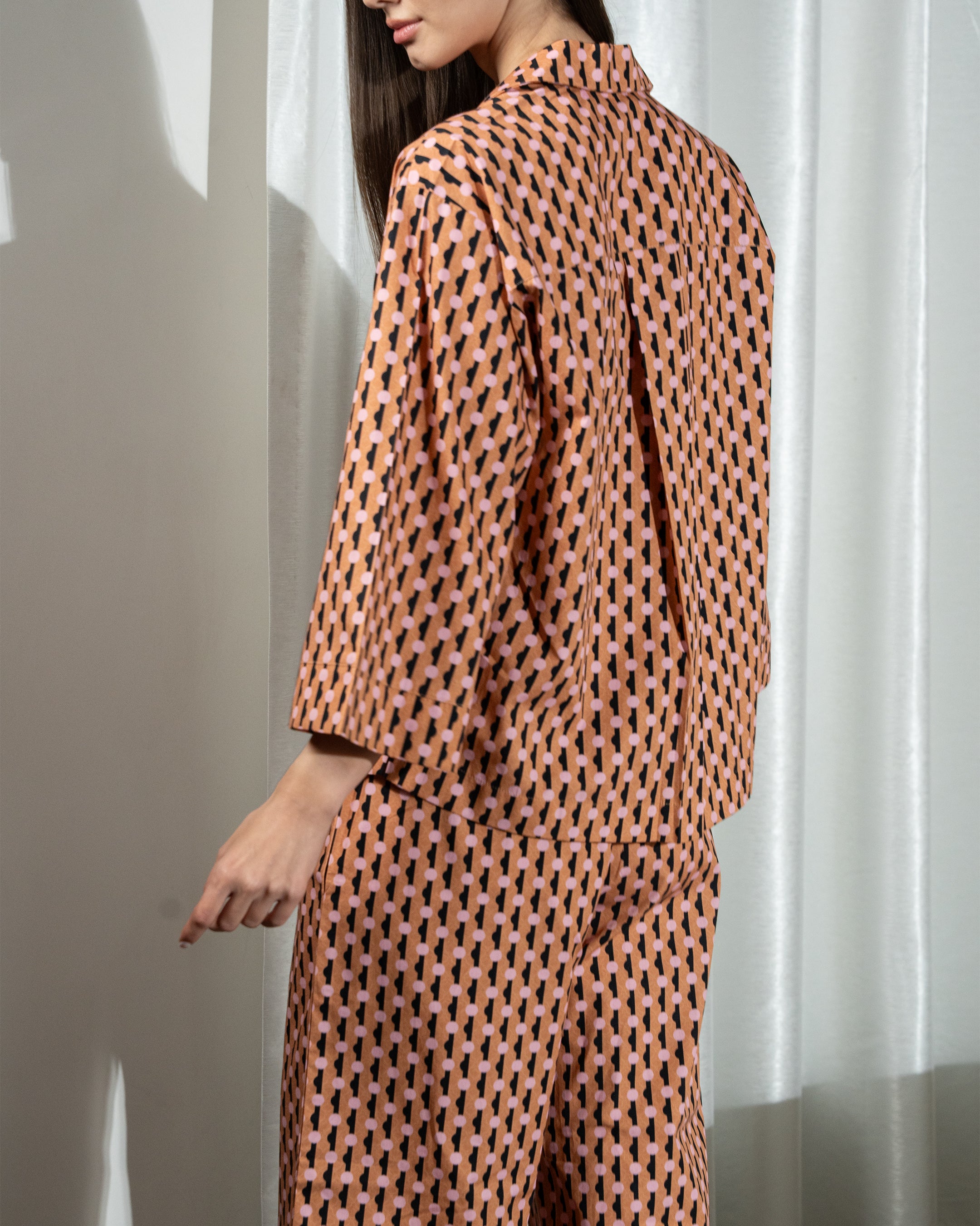 Person wearing a patterned outfit against a neutral background