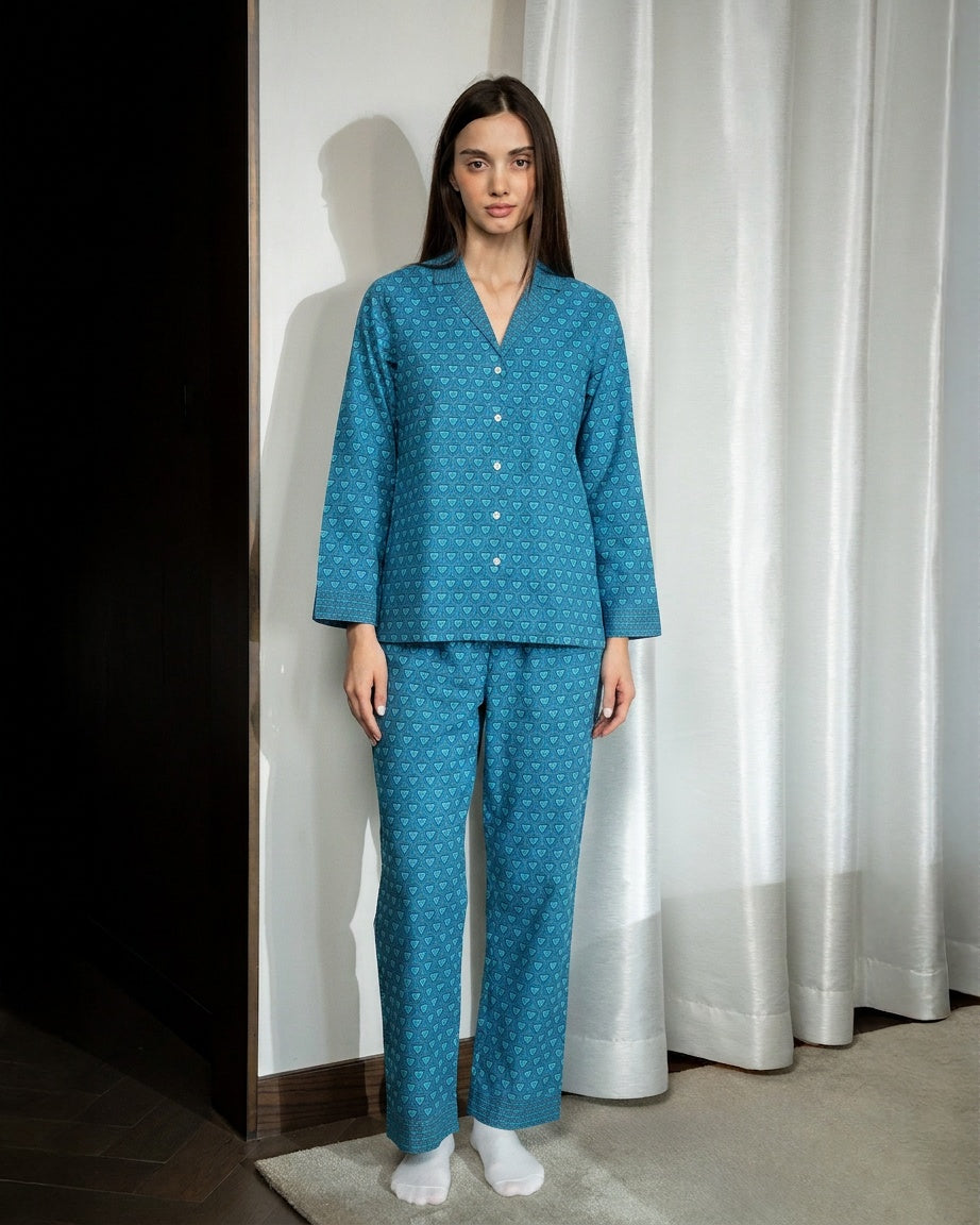 Woman wearing a blue polka dot pajama set standing against a white curtain.